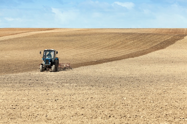 Foto un tractor arando un campo ubicado en la tierra durante la siembra.