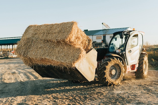 Un tractor arrastra fardos de paja en su pala. trabajos conceptuales