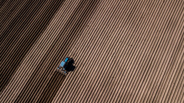 Tractor azul arando el campo. Fotografía aérea con drone