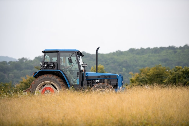 Foto un tractor azul trabajando en tierras de cultivo