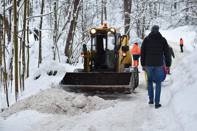 El tractor borra el camino cubierto de nieve. limpieza de obras viales en invierno. limpieza de carreteras de automóviles de nieve y hielo