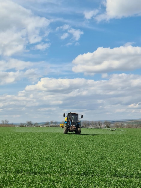 Un tractor en un campo con cielo azul y nubes.