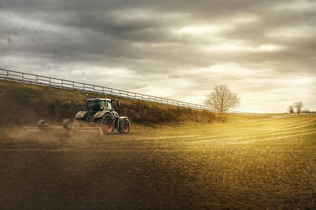 Un tractor en un campo con una valla al fondo.