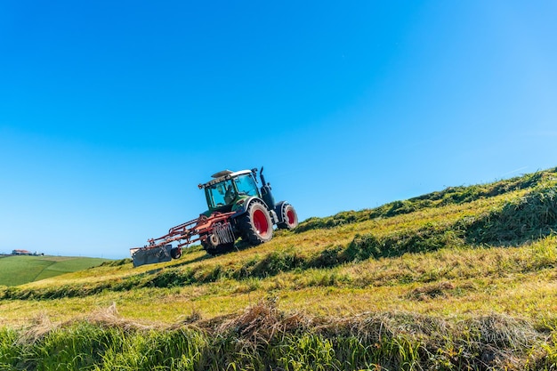 Foto un tractor está conduciendo por una ladera arando el césped