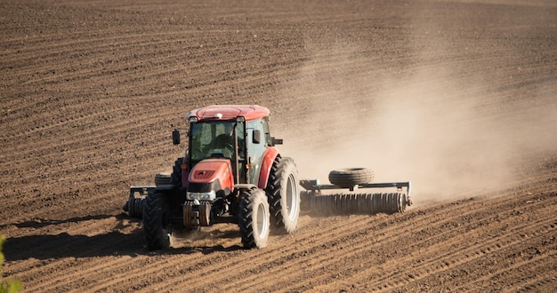 Tractor cultivando campo agrícola en acción enfoque selectivo