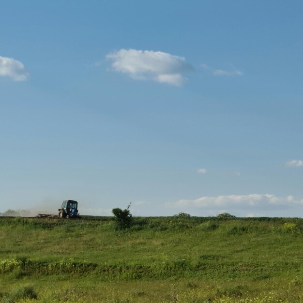Un tractor está en un campo con un cielo azul de fondo.