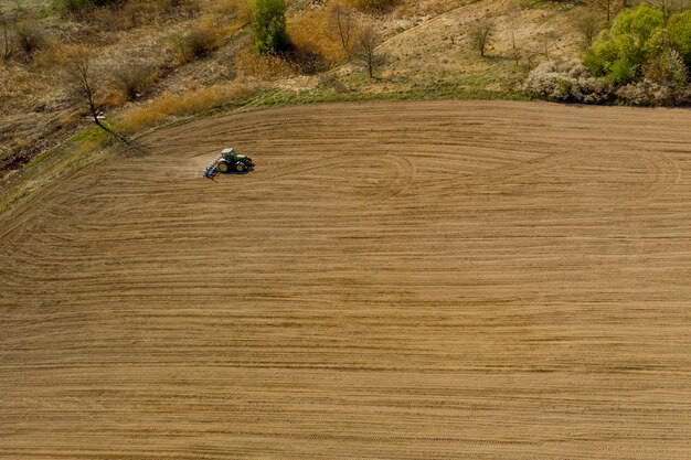 Tractor grande de vista aérea cultivando un campo seco.