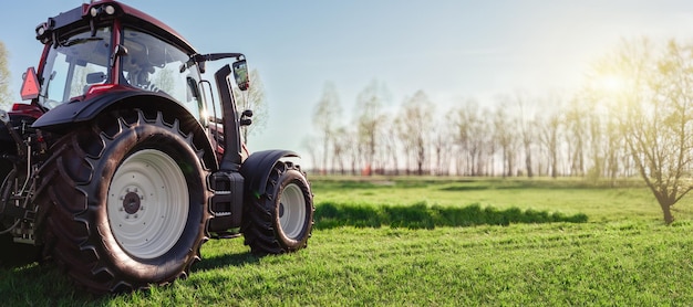 Tractor iluminado pelo sol no campo verde em Sunrise Banner