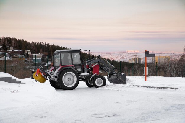 Tractor con implementos montados quita nieve en invierno en la ciudad