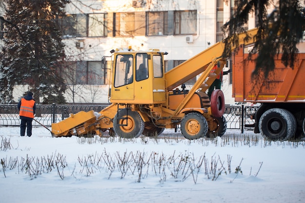 Tractor limpiando la carretera de la nieve. La excavadora limpia las calles de grandes cantidades de nieve en la ciudad. Los trabajadores barren la nieve de la carretera en invierno, limpiando la carretera de la tormenta de nieve.