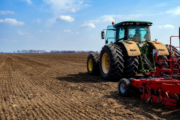 Tractor na estrada por campo agrícola contra o céu