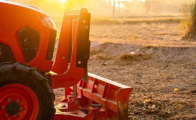 Foto tractor naranja estacionado en la granja de arroz en la mañana de verano con luz solar maquinaria agrícola en la granga de agricultura concepto de agricultura inteligente vehículo en la granda maquinaria de ahorro de mano de obra equipamiento para la plantación