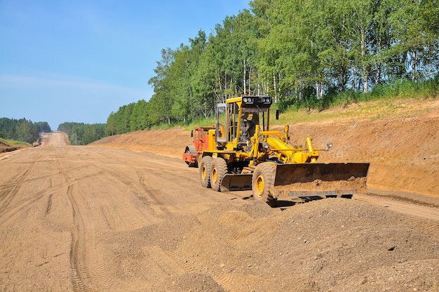 Un tractor raspador amarillo nivela el suelo Construcción de una nueva carretera