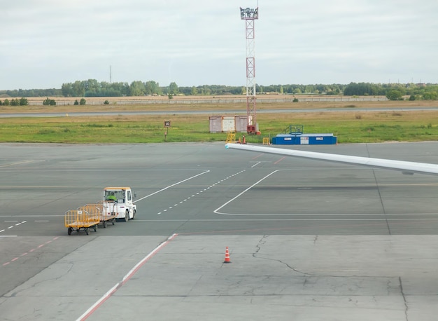 Foto un tractor con un remolque para el transporte de equipaje de pasajeros entre un avión y una terminal de aeropuerto transporte de equipaje del avión al aeropuerto