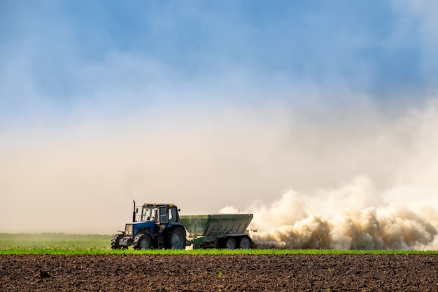 Tractor rociando fertilizantes en el suelo a principios de la primavera. Mantener la fertilidad del suelo, mejorar el desarrollo de los cultivos.