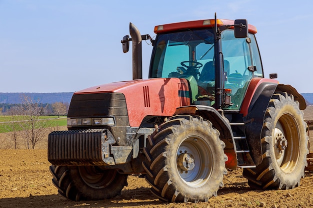 Tractor rojo en un campo agrícola en un día soleado de primavera.