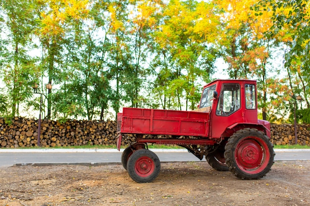 Tractor rojo con un tronco en el frente.