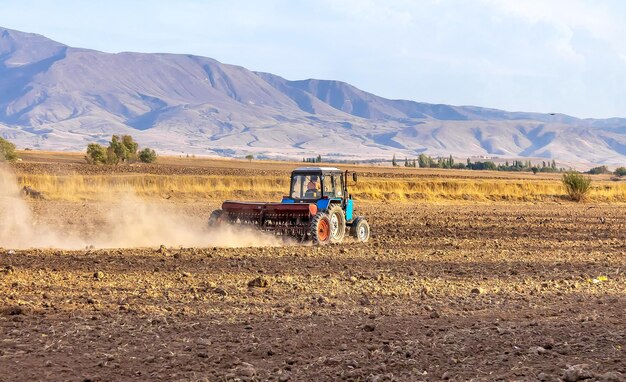 Foto tractor con una sembradora en un campo en el paisaje de otoño