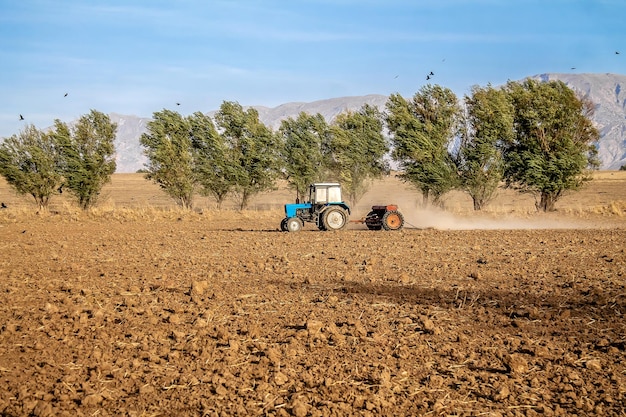 Foto tractor con una sembradora en un campo en el paisaje de otoño