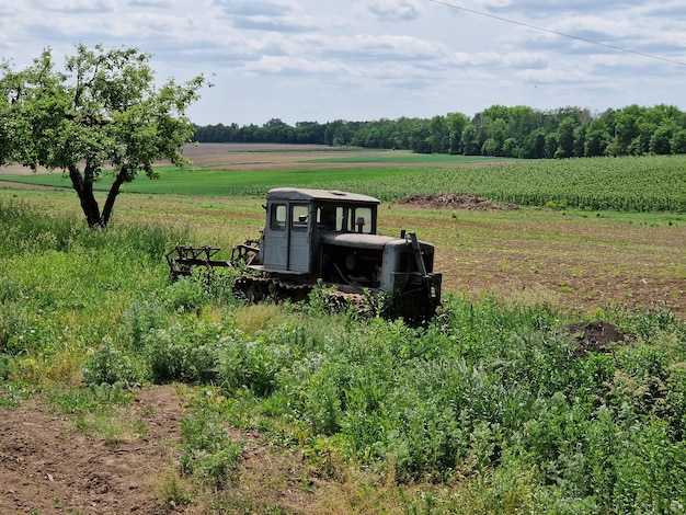 Un tractor se sienta en un campo con un árbol en el fondo.