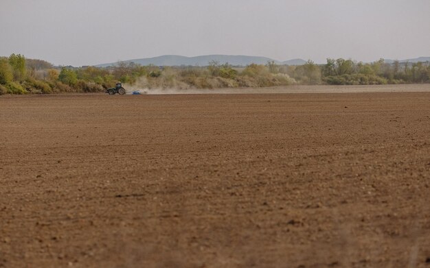 El tractor termina de arar el campo Tractor en un campo en una granja