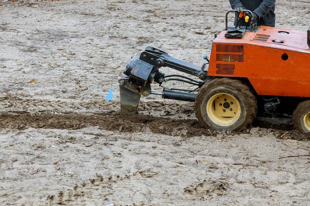 Tractor utilizado para el movimiento de tierras de la tubería una excavación de tierra con jardín en el suelo para sistema de riego