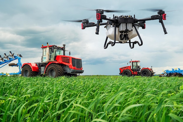 Los tractores cultivan el suelo en las zonas rurales El concepto de agricultura tecnológica Las tecnologías modernas en la agricultura Un dron industrial vuela sobre un campo verde