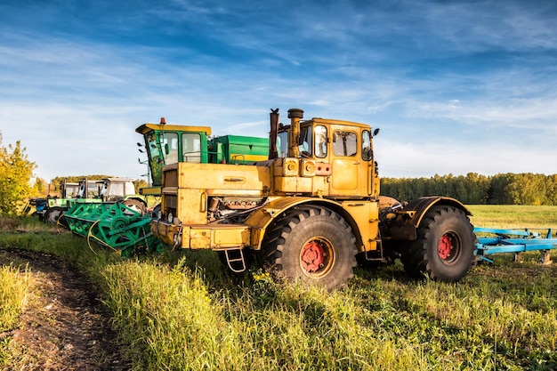 Tractores de ruedas y cosechadora de pie en una fila en un campo agrícola