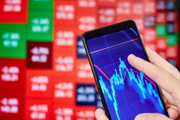 Trader analisa dados do mercado de ações em smartphone