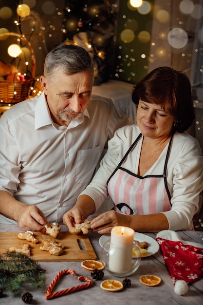 Tradición familiar navideña mujer y hombre de edad para cocinar galletas de jengibre en la cocina foto vertical