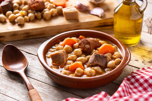 Tradicional espanhol cocido madrileño. Ensopado de grão de bico na mesa de madeira