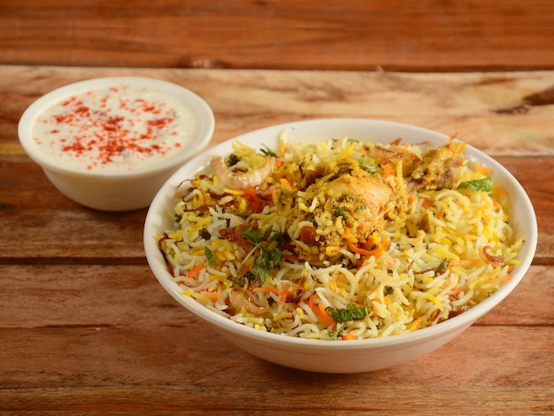 Tradicional Hyderabadi Chicken dum Biryani feito de arroz Basmati cozido com especiarias masala servido com foco seletivo de iogurte