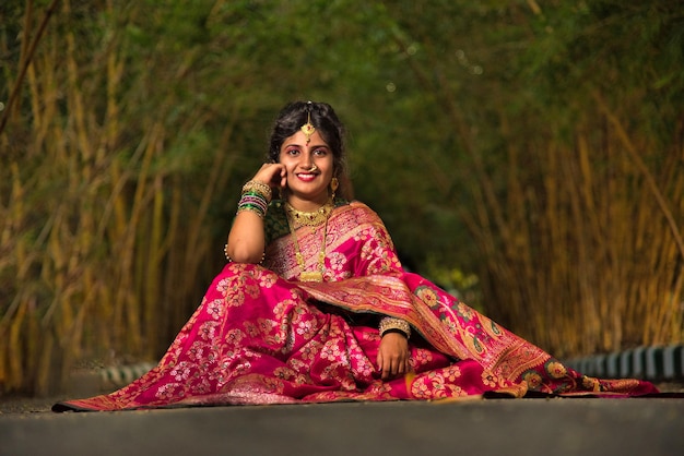 Tradicional india hermosa joven en sari posando al aire libre en el parque