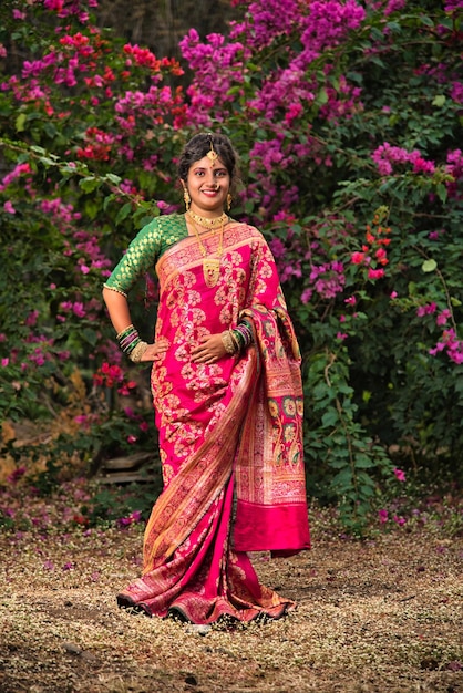 Tradicional india hermosa joven en sari posando al aire libre en el parque