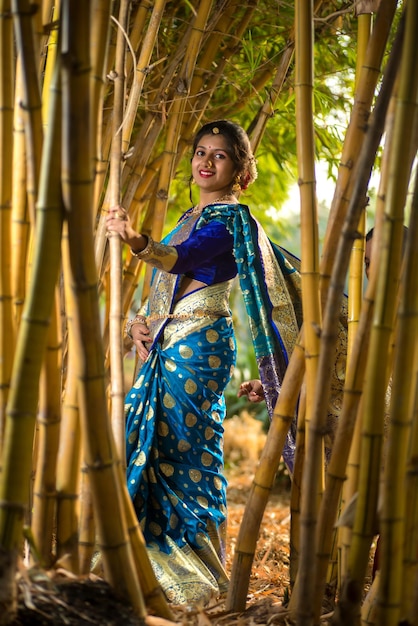 Tradicional india hermosa joven en sari posando al aire libre en el parque