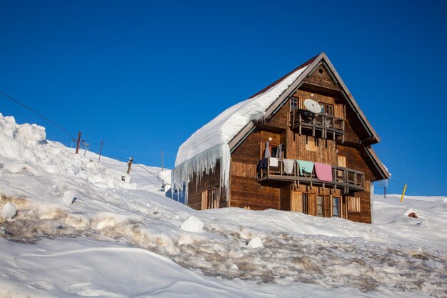 Tradicional linda casa de madeira cena invernal com cabana de neve em uma estância de esqui