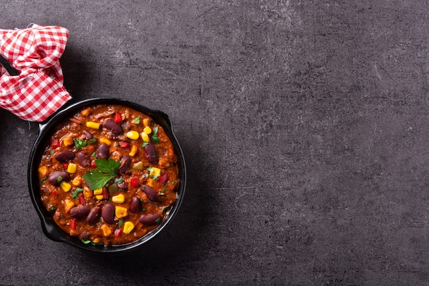 Tradicional mexicano tex mex chili con carne en sartén de hierro sobre fondo de piedra negra