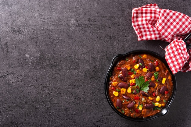 Tradicional mexicano tex mex chili con carne em uma panela de ferro com fundo de pedra preta