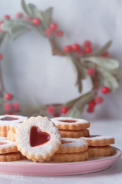 Tradicional Natal Linzer cookies preenchido com gelÃ © ia vermelha na mesa de luz com decoraÃ§Ãµes de Natal