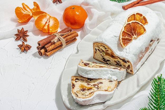 Tradicional pastel de Navidad alemán robado Pastelería europea fragante pan casero con especias y frutos secos Ramas de árboles de Navidad y decoraciones espacio de copia de fondo blanco