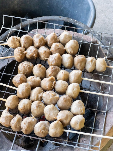 Las tradicionales albóndigas de cerdo al estilo tailandés con las brochetas se asan a la parrilla en una rejilla metálica