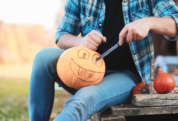 Tradiciones de otoño y preparativos para la fiesta de Halloween. Una casa en la naturaleza, una lámpara hecha de calabazas se corta en la mesa.