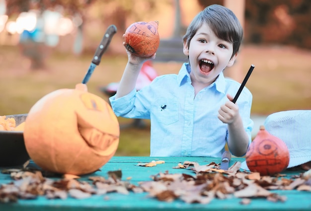 Tradiciones de otoño y preparativos para la fiesta de Halloween. Una casa en la naturaleza, una lámpara hecha de calabazas se corta en la mesa.