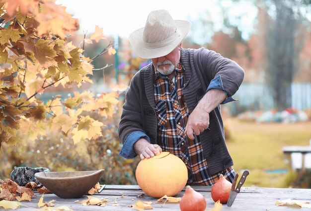 Tradiciones de otoño y preparativos para la fiesta de Halloween. Una casa en la naturaleza, una lámpara hecha de calabazas se corta en la mesa.