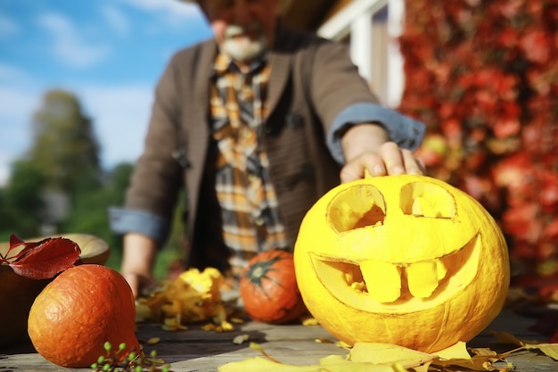 Tradiciones de otoño y preparativos para la fiesta de Halloween. Una casa en la naturaleza, una lámpara hecha de calabazas se corta en la mesa.