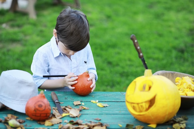 Tradiciones de otoño y preparativos para la fiesta de Halloween. Una casa en la naturaleza, una lámpara hecha de calabazas se corta en la mesa.