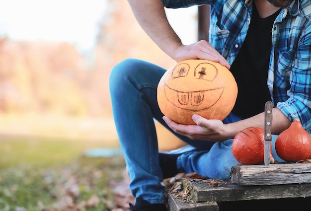 Tradiciones de otoño y preparativos para la fiesta de Halloween. Una casa en la naturaleza, una lámpara hecha de calabazas se corta en la mesa.