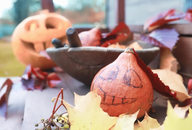 Tradiciones de otoño y preparativos para la fiesta de Halloween. Una casa en la naturaleza, una lámpara hecha de calabazas se corta en la mesa.