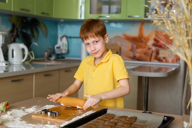 Tradiciones de Pascua Concepto de comida Preparación para hornear Pascua Retrato de un niño pelirrojo mirando la cámara y haciendo masa para hornear galletas