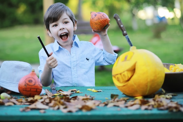 Tradições de outono e preparativos para o feriado de Halloween. Uma casa na natureza, uma lâmpada feita de abóboras está sendo cortada à mesa.